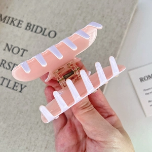 Détail d'une pince à cheveux en acétate rose et lavande avec finition brillante et ressort