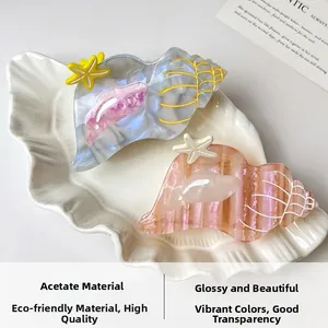 Detailed view of conch and starfish acetate hair claws on a shell tray with ocean vibes
