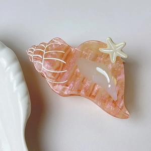 Detail view of acetate seashell hair claw clip with starfish and dolphin accents