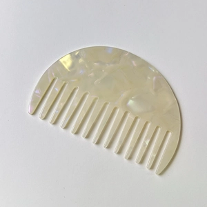 Detailed view of the marble texture and wide teeth on a semi-circular acetate hair comb