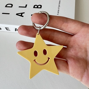 Yellow acrylic star keychain with hollow smiley face and silver metal spring ring