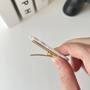 Dettaglio ravvicinato della molletta in acetato marmorizzato con clip in metallo dorato