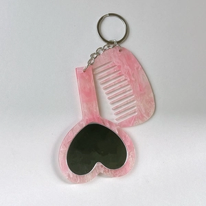 Ensemble porte-clés miroir cœur et peigne en résine marbrée rose sur fond blanc