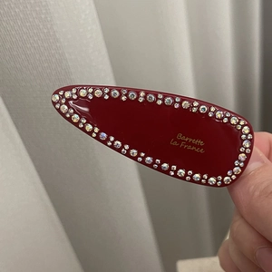 Close-up of a burgundy oval hair clip with colorful rhinestones and gold Barrette lettering