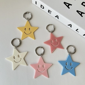 Set of five colorful acrylic star-shaped smiley face keychains on white leather