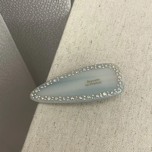 Close-up of light blue acetate hair clip with sparkling rhinestones and French lettering