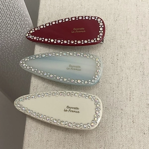 Three-piece set of rhinestone-edged acetate hair clips in burgundy, blue, and cream colors
