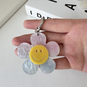 Close-up of a translucent acrylic flower keychain with glitter and a yellow smiley face