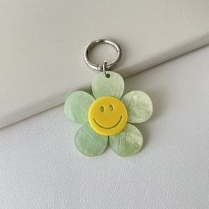 Detailed macro view of light green glittery acrylic smiley flower charm on leather