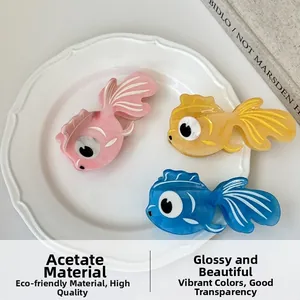 Three acetate goldfish hair claws in pink, yellow and blue on white ceramic plate
