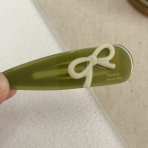 Close-up of olive green acetate hair clip with cream bow and France Handmade engraving