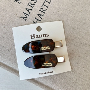 Close-up of tortoise shell barrette with gold metal clip on brand display card