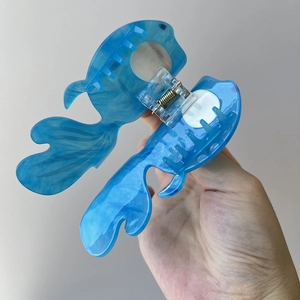 Detail showing marble texture on blue acetate fish-shaped hair claw clip with metal spring