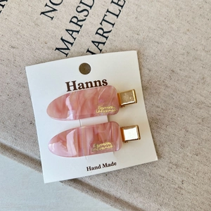 Detail showing pink marble texture hair clips with gold letters on a display card