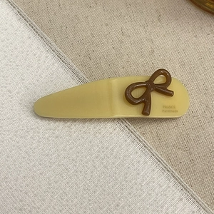 Macro detail of French handmade acetate hair clip with bow design on lace fabric