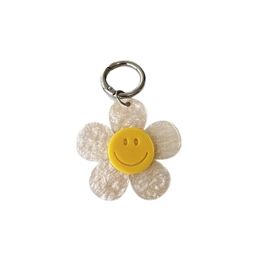 Colorful acrylic glitter flower keychain with a yellow smiley face on white background