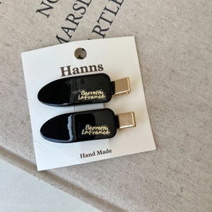 Detail view of two black glossy hair clips with gold Barrette La France lettering