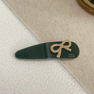 Detail of dark green acetate hair clip with a brown bow and gold France Handmade logo