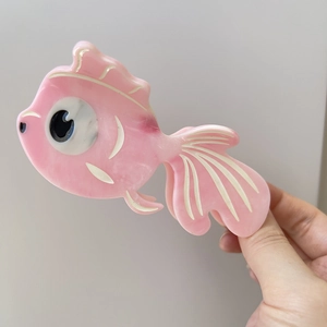 Detailed macro view of a pink acetate fish-shaped hair claw clip with smooth texture