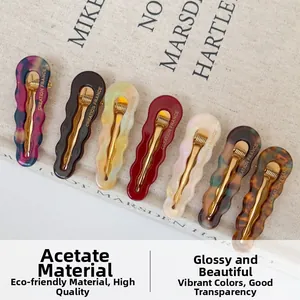 Detail showing seven wave-shaped acetate hair clips in assorted colors with gold metal base