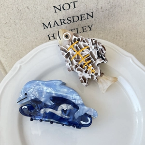 Détails de pinces à cheveux poisson et dauphin aux textures marbrées bleu et tortue