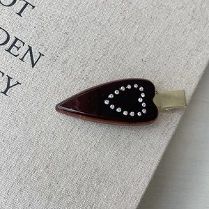 Dettaglio di un fermaglio per capelli in acetato marrone scuro con cuore di strass