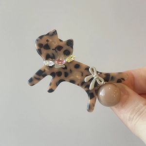 Detail of leopard print acetate cat hair clip with rhinestones and ribbon bow