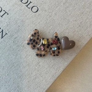 Detailed shot of leopard print Scottie dog hair clip with colorful rhinestones on book