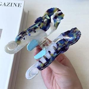 Detailed view of seahorse-shaped acetate hair claw with blue marble texture and metal spring