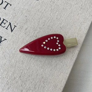 Dettaglio di un fermaglio per capelli a cuore in acetato bordeaux con 14 strass colorati