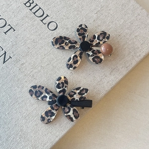 Detail of leopard print flower hair clips with acetate finish on textured background