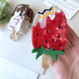 Detail view of strawberry popsicle shaped acetic acid hair claw clip with pearly texture