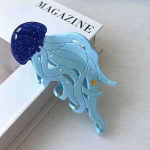Detailed close-up of a blue jellyfish hair claw clip with glitter and starfish detail