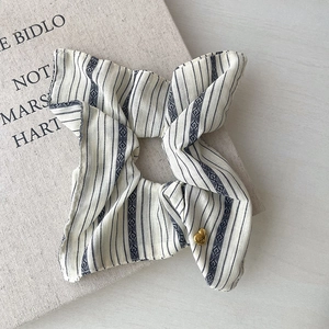 Detailed view of blue striped scrunchie with elegant golden heart charm and polka dots