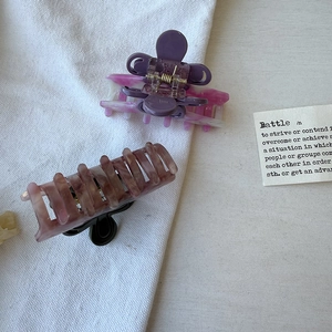 Close-up of acetic acid flower hair claws showing marble and amber patterns on woven fabric