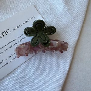 Detailed view of pink marble acetate hair claw clip with dark green flower pattern