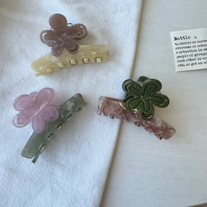 Three-piece set of acetate flower hair claws in creamy yellow, grey green, and marble red