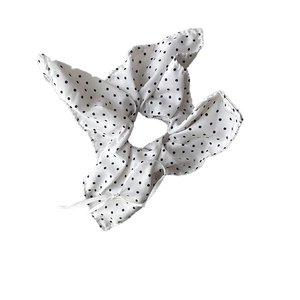 Polka dot cream scrunchie with a white ribbon bow on a clean white background
