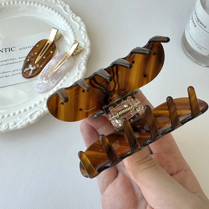 Close-up of a large amber acetate hair claw clip with tortoise shell pattern and metal spring