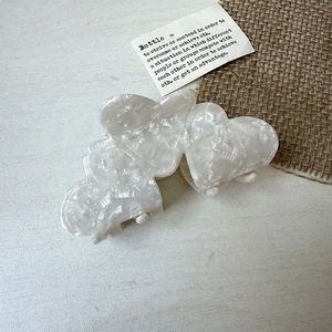 Detail of heart-shaped marble acetate hair claw clip with white cloud textures