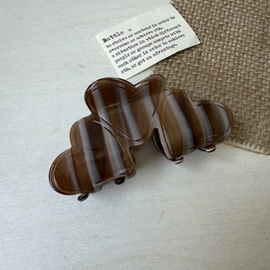 Detail of elegant heart-shaped amber acetate hair claw clip with a marble texture