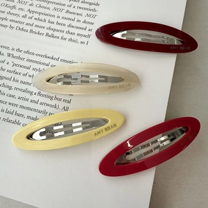 Detailed view of hollow acetate oval hair clips in four colors on an open book