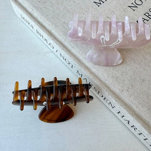 Detailed view of acetate hair claws in marble pink and tortoiseshell with bow and rhinestones