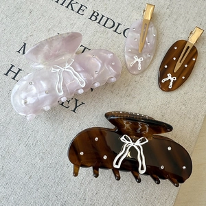 Elegant bow-knot hair claw clips set with rhinestones on marble and amber acetate