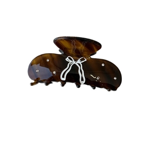Amber acetate claw clip with white bow design and rhinestones on a white background