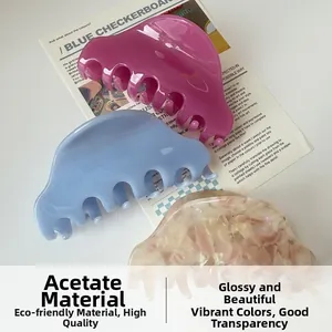 Primo piano di tre mollette per capelli in acetato marmorizzate e traslucide su una rivista
