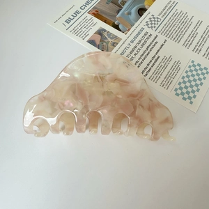Dettaglio di un grande fermaglio per capelli in acetato con motivo marmorizzato rosa