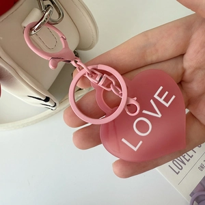 Détail d'un porte-clés cœur rose avec texte LOVE blanc et fermoir mousqueton assorti