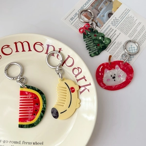 Mini acetate animal fruit comb keychains in watermelon and cat shapes on a ceramic plate