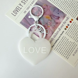 Détail d'un porte-clés cœur blanc mat avec texte LOVE en relief 3D sur un fond élégant